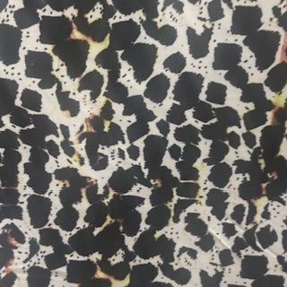 4 way Stretch tricot fabric with black and yellow spots on a beige back ground | Spandex Palace